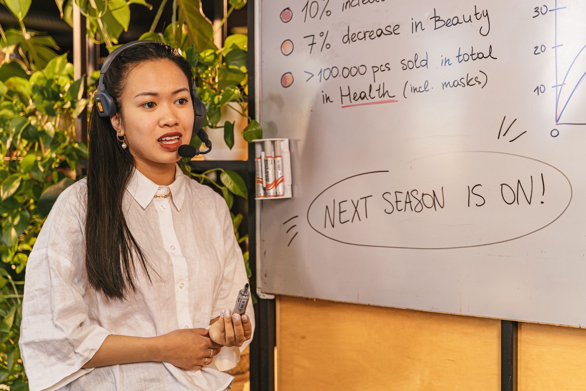 Woman presenting on a whiteboard while wearing a headset