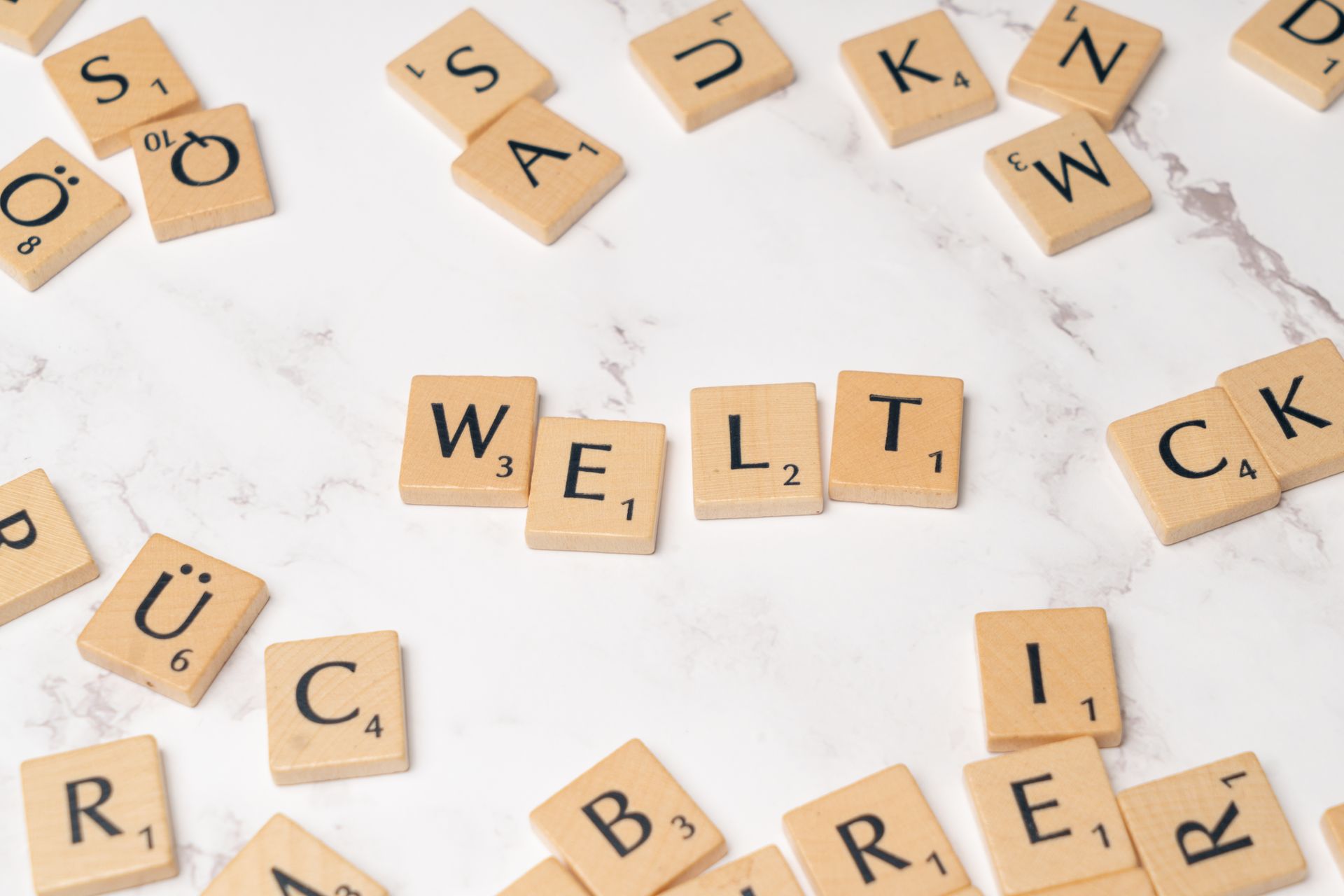 Wooden letter tiles spelling WELT on a white marble surface