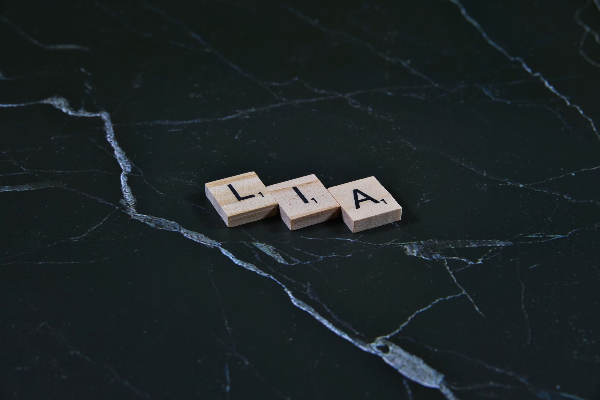 Wooden letter tiles arranged on dark marble