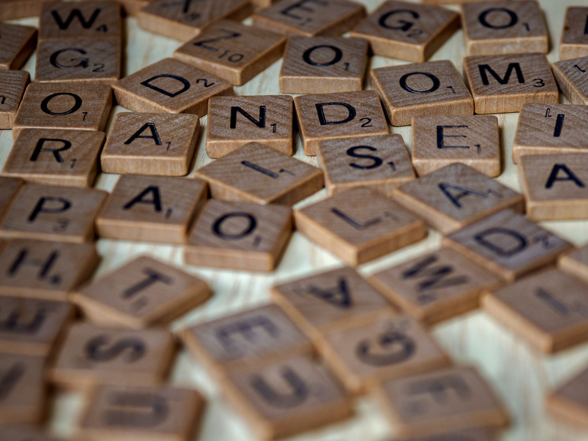 Scattered wooden Scrabble tiles with letters and point values